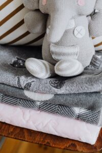 Stack of baby blankets with a soft elephant toy, perfect for a nursery.